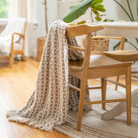 Textured blanket draped over a wooden chair in a cozy living room setting.
