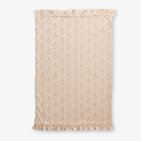 Eyelet ruffle throw laid flat on a white surface.