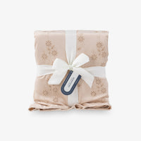 Eyelet ruffle throw folded nealty on a white surface tied in a bow.