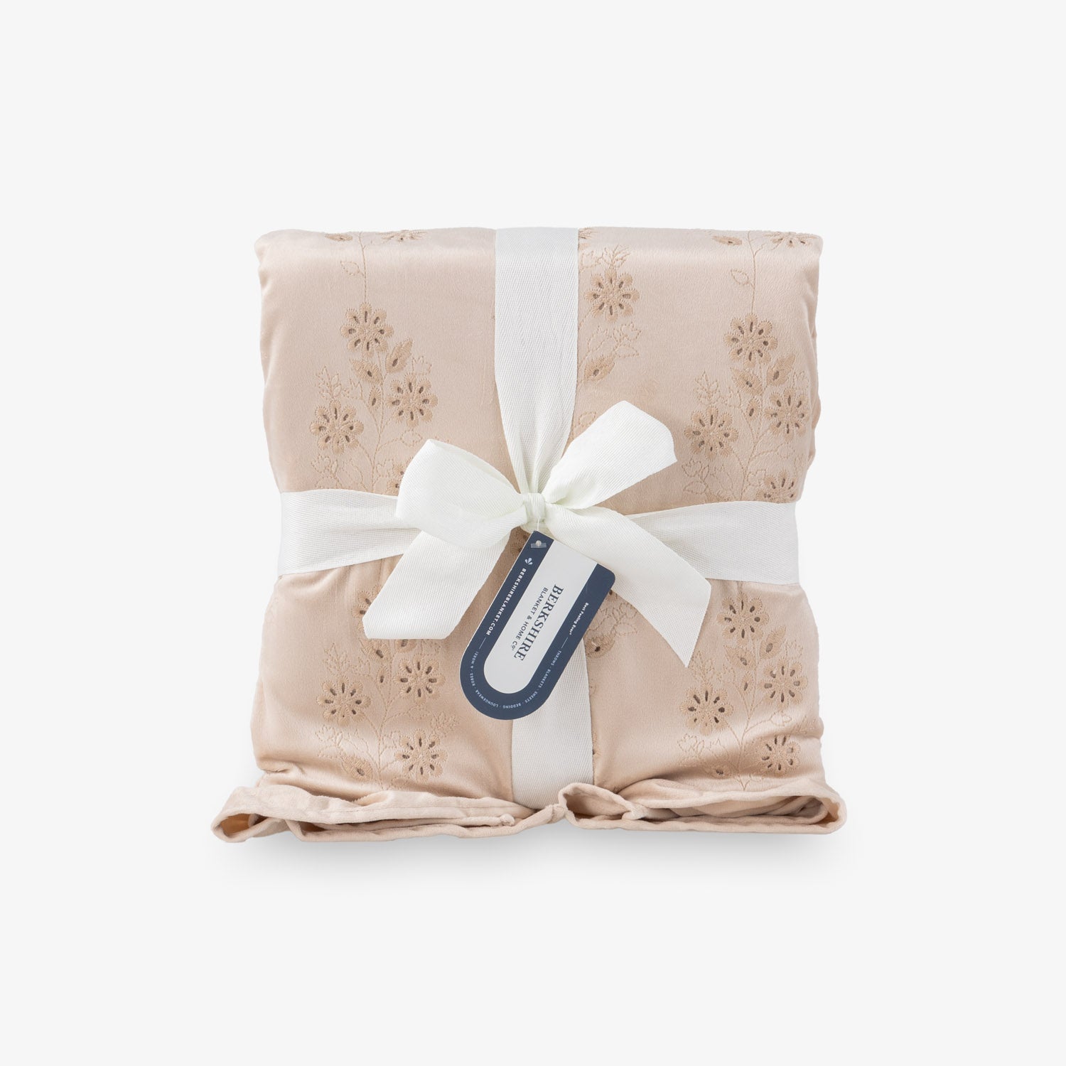 Eyelet ruffle throw folded nealty on a white surface tied in a bow.