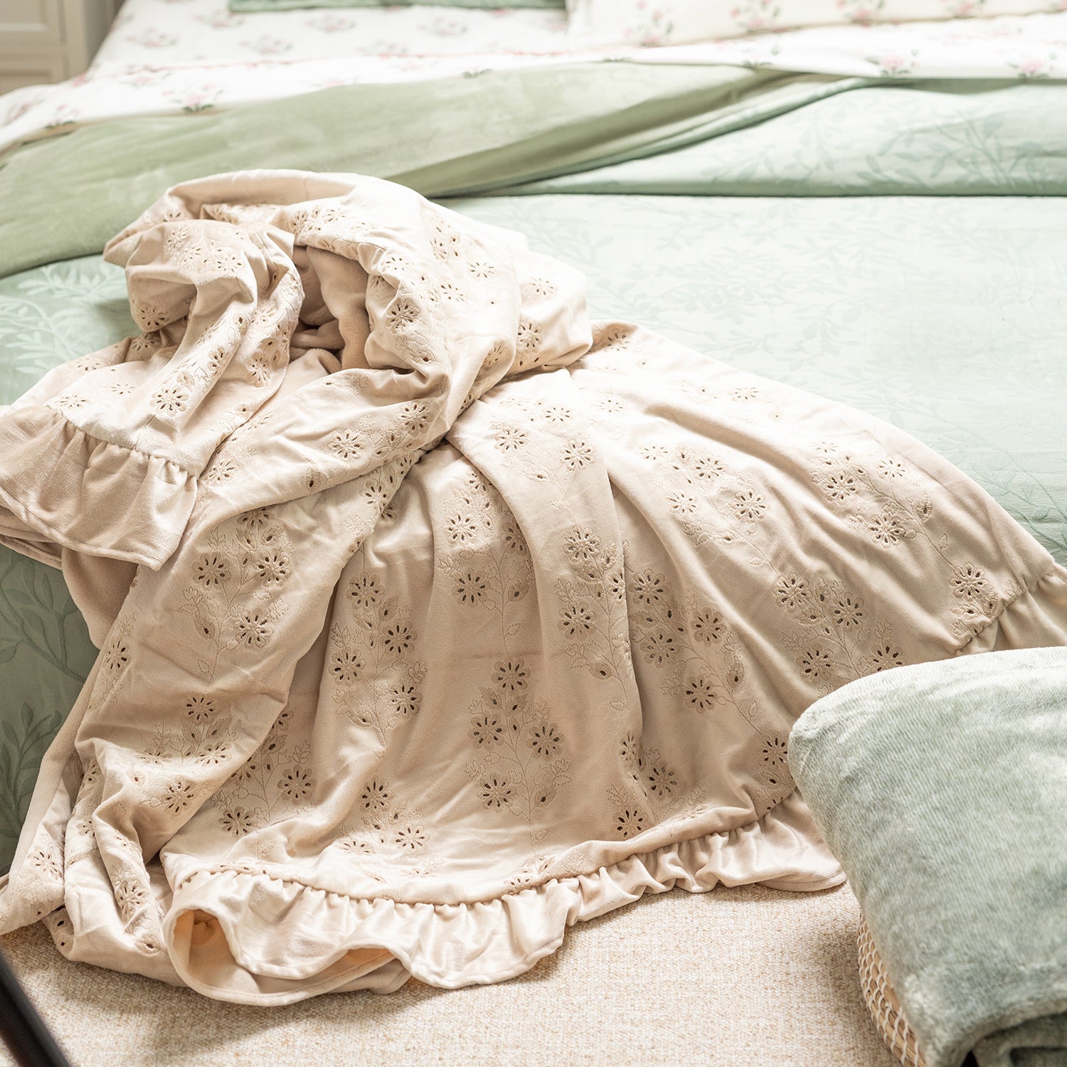 Beige embroidered fabric on a bed with green bedding