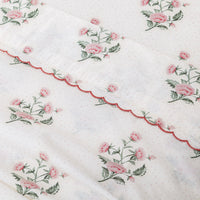 Floral patterned fabric with pink flowers and green leaves on a white background