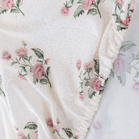 Floral patterned fabric with pink flowers and green leaves on a white background