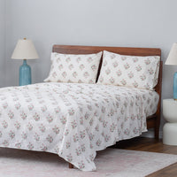 Floral-patterned bedspread on a bed with wooden headboard and side tables.