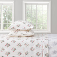 Floral bed sheet set on a bed with pillows in a room with windows.