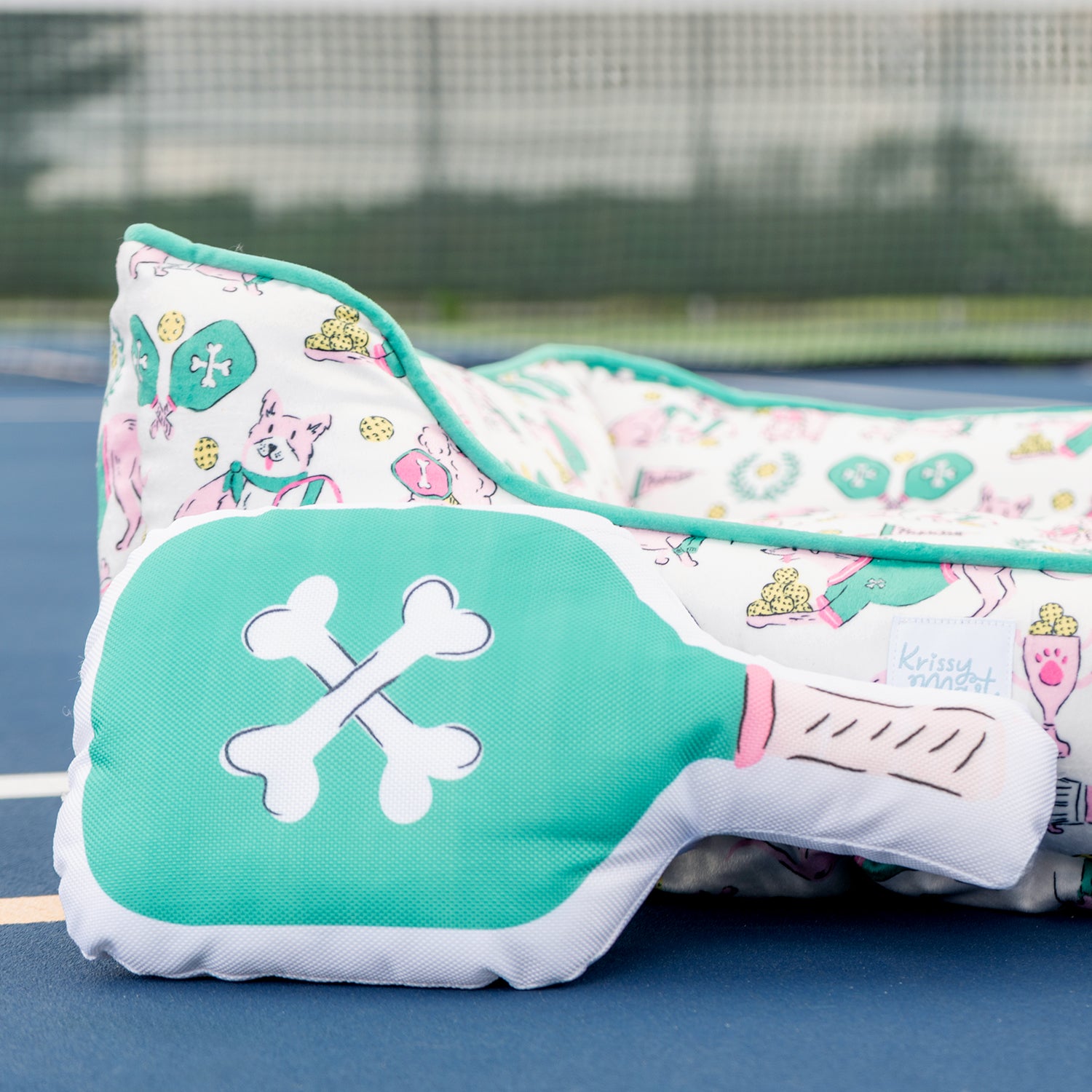Teal pet bed with cartoon dog design on a blue surface