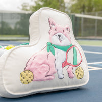 Pillow with a pink and white dog design on a tennis court