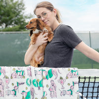 Woman holding a small brown dog outdoors with a patterned fabric in the foreground.