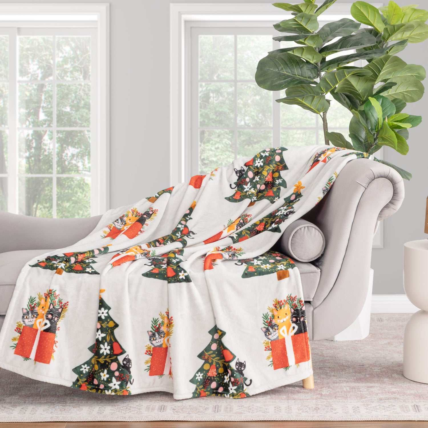 Decorative blanket with Christmas tree and gift design draped over a chair in a living room.