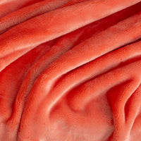 Close up of a neon orange velvety throw diplaying its silky smooth and plush texture.