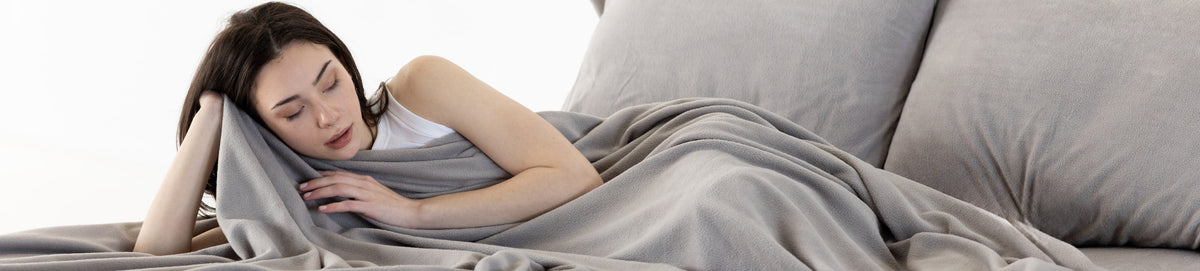 Woman laying in bed with grey sheets on the bed