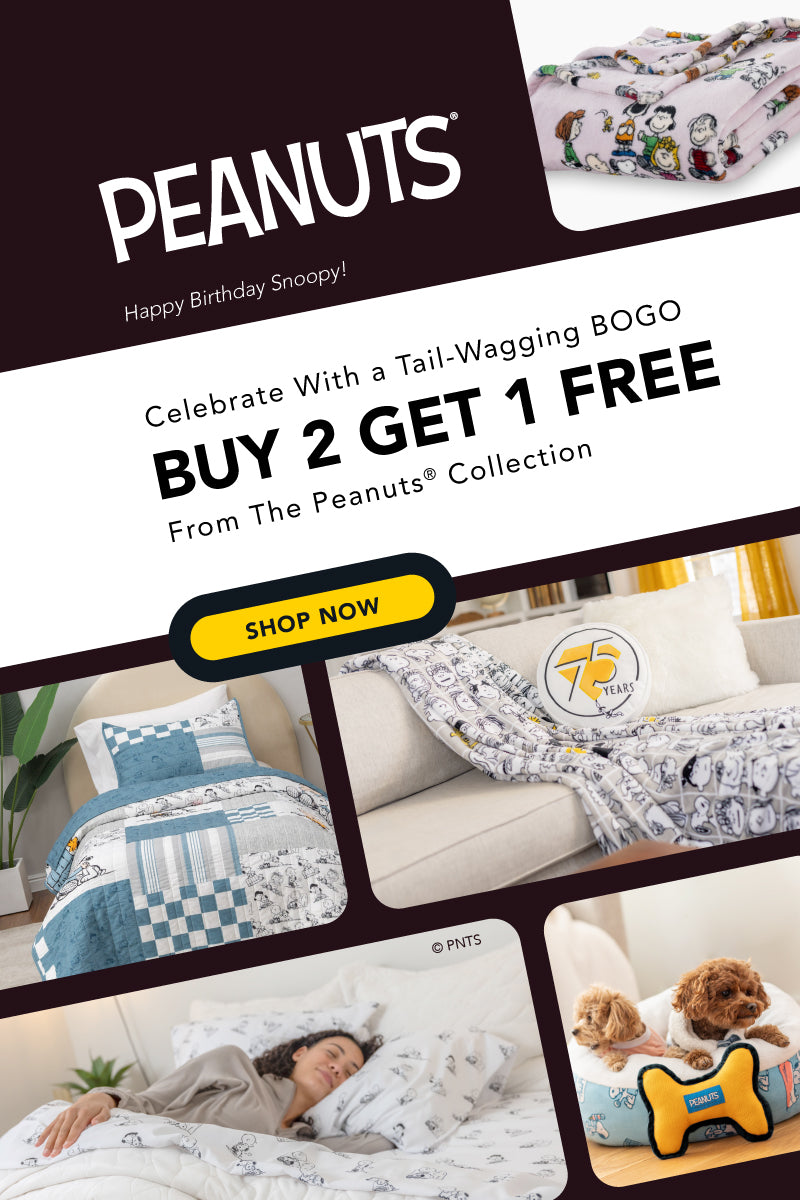 promotional graphic for the Peanuts® Collection celebrating Snoopy’s birthday. The top features the Peanuts® logo and an image of a folded blanket with Peanuts characters. Text reads: “Celebrate with a Tail-Wagging BOGO – Buy 2 Get 1 Free from the Peanuts® Collection.” A yellow “Shop Now” button is prominently displayed. Below are product images including a Peanuts-themed bedding set on a bed, a white and black character blanket on a couch with a round "75 Years" pillow, a woman sleeping in Peanuts sheets