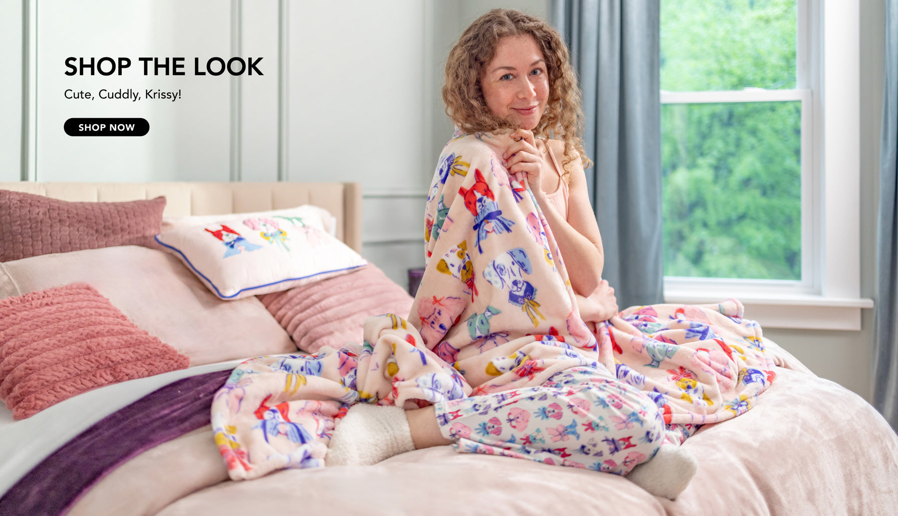 SHOP THE LOOK. Cute, Cuddle, Krissy. Shop Now. Image of a girl in a room styled with pink and purple product, plush a throw, pants, and pillow with dog print.
