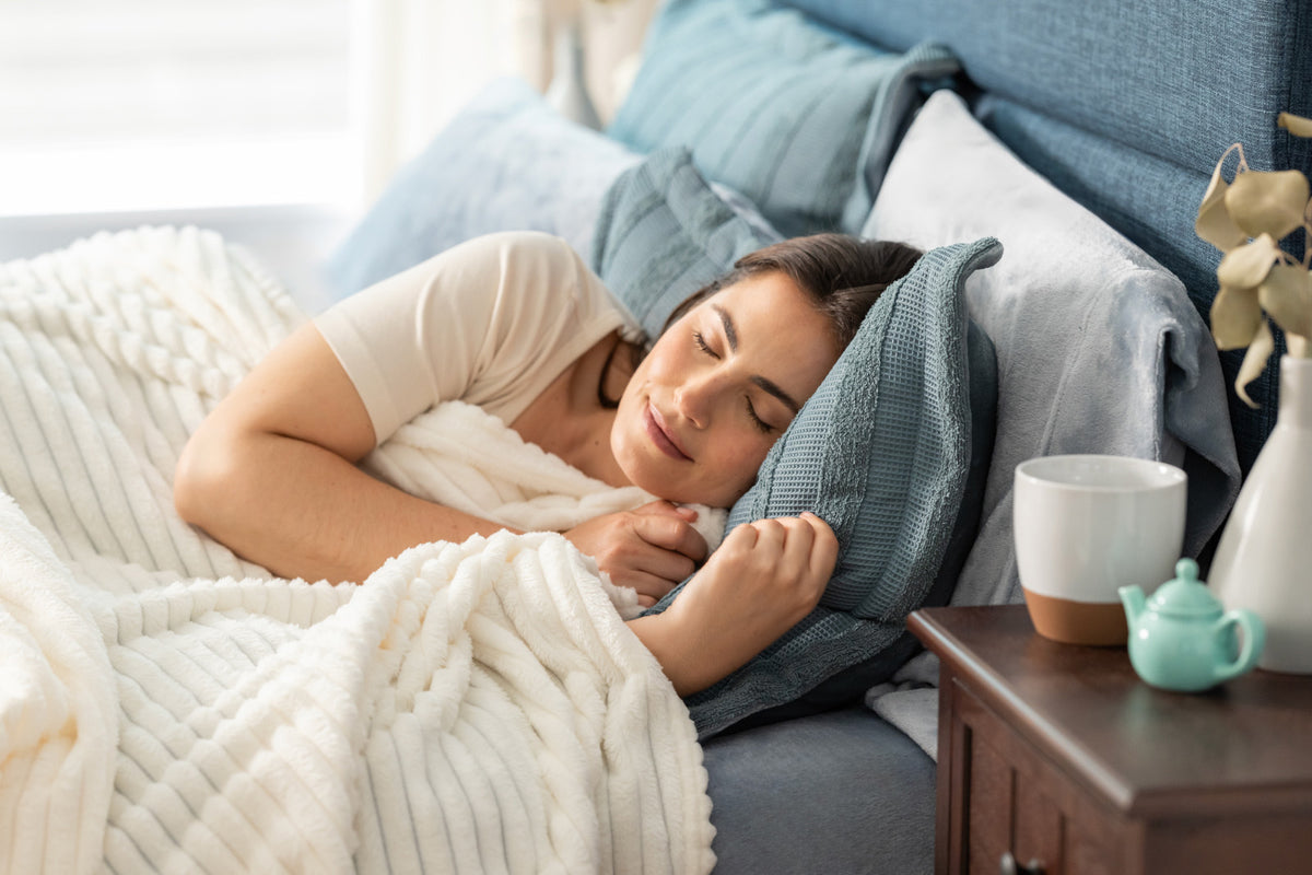 Image of woman sleeping gin a bed styled with blue and white products
