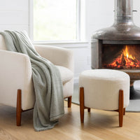 Farmhouse Sage throw draped over a chair, styled next to a modern fireplace and cozy seating.