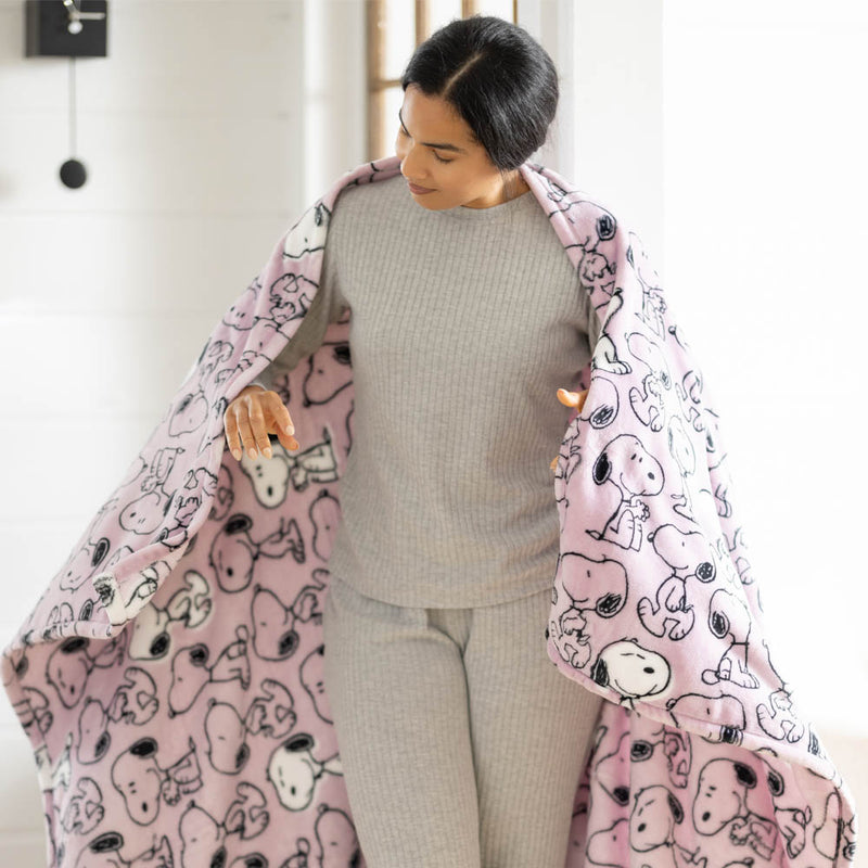 Woman holding a pink blanket with cartoon characters, wearing a gray outfit.