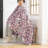 Person sitting on a chair wearing a pink blanket with cartoon characters