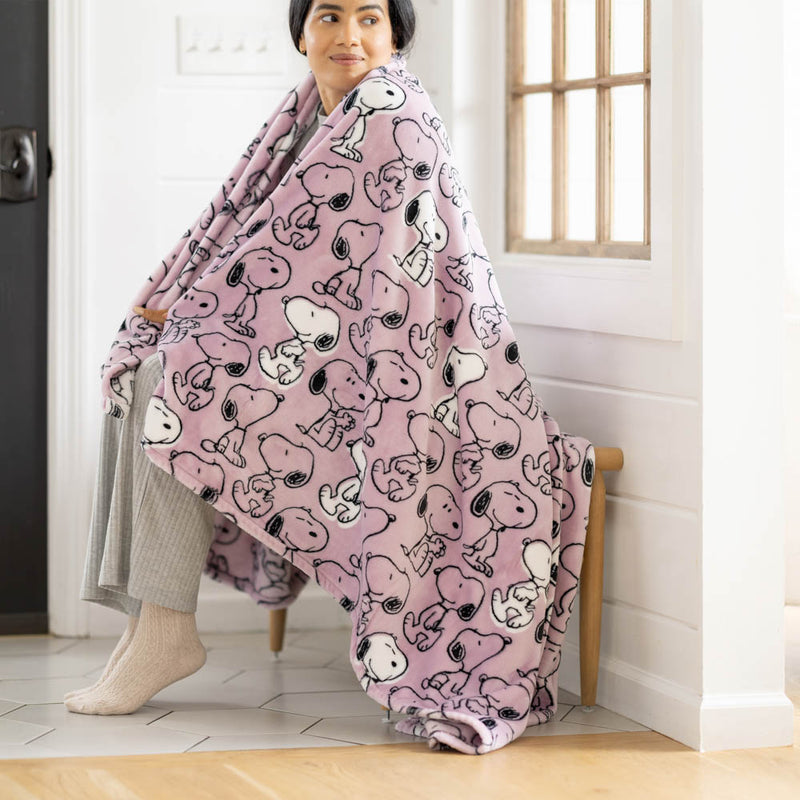 Person sitting on a chair wearing a pink blanket with cartoon characters