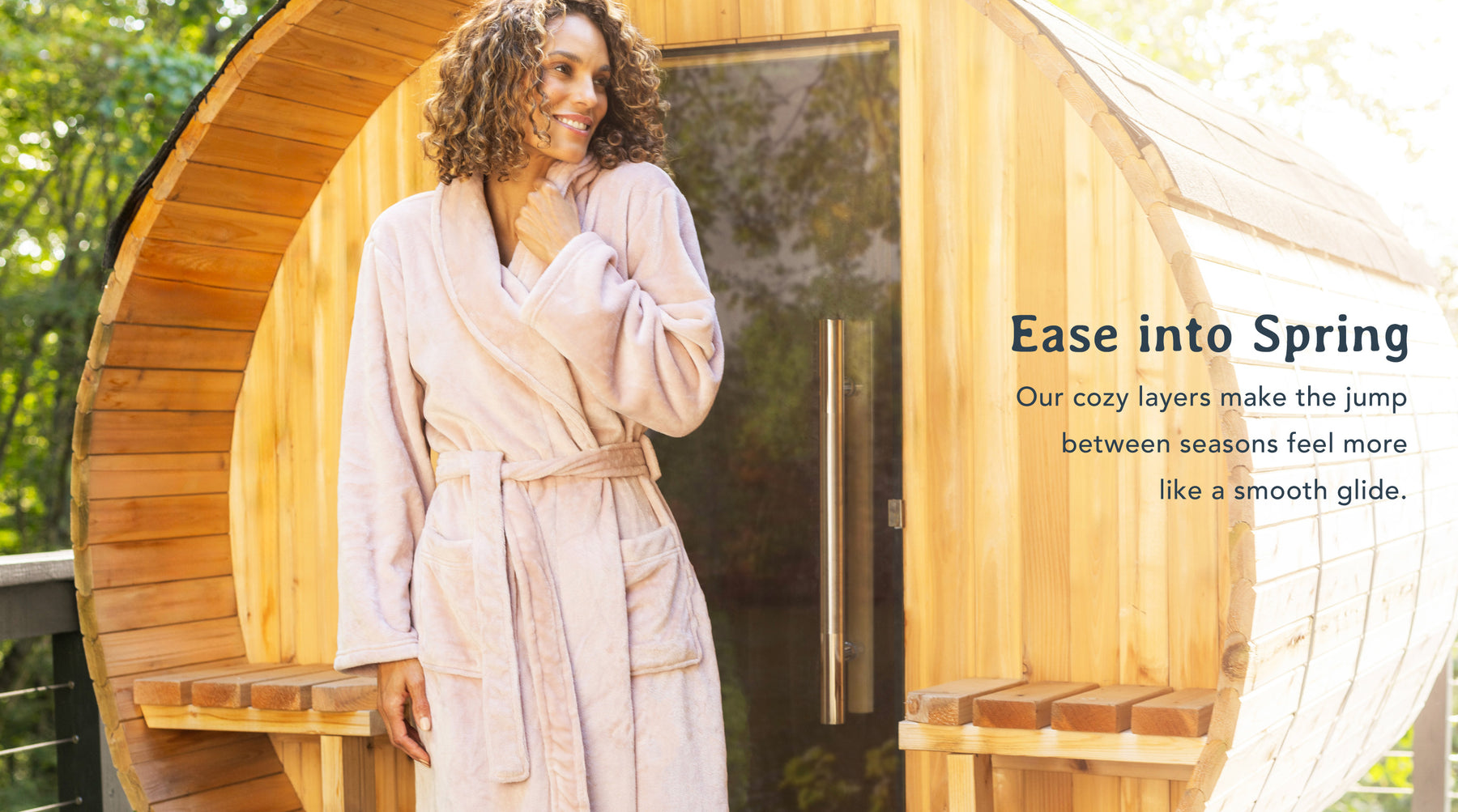 Ease into spring - our cozy layers make the jump between seasons feel more like a smooth glide. Features a woman in our VelvetLoft Robe standing outside of a sauna.