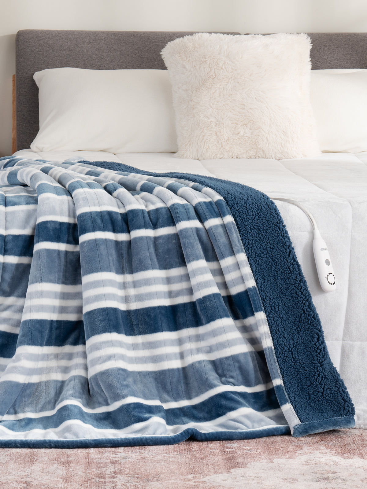 Heated collection image featuring our Varigated Stripe VelvetLoft Sherpa Throw draped over a white bed.