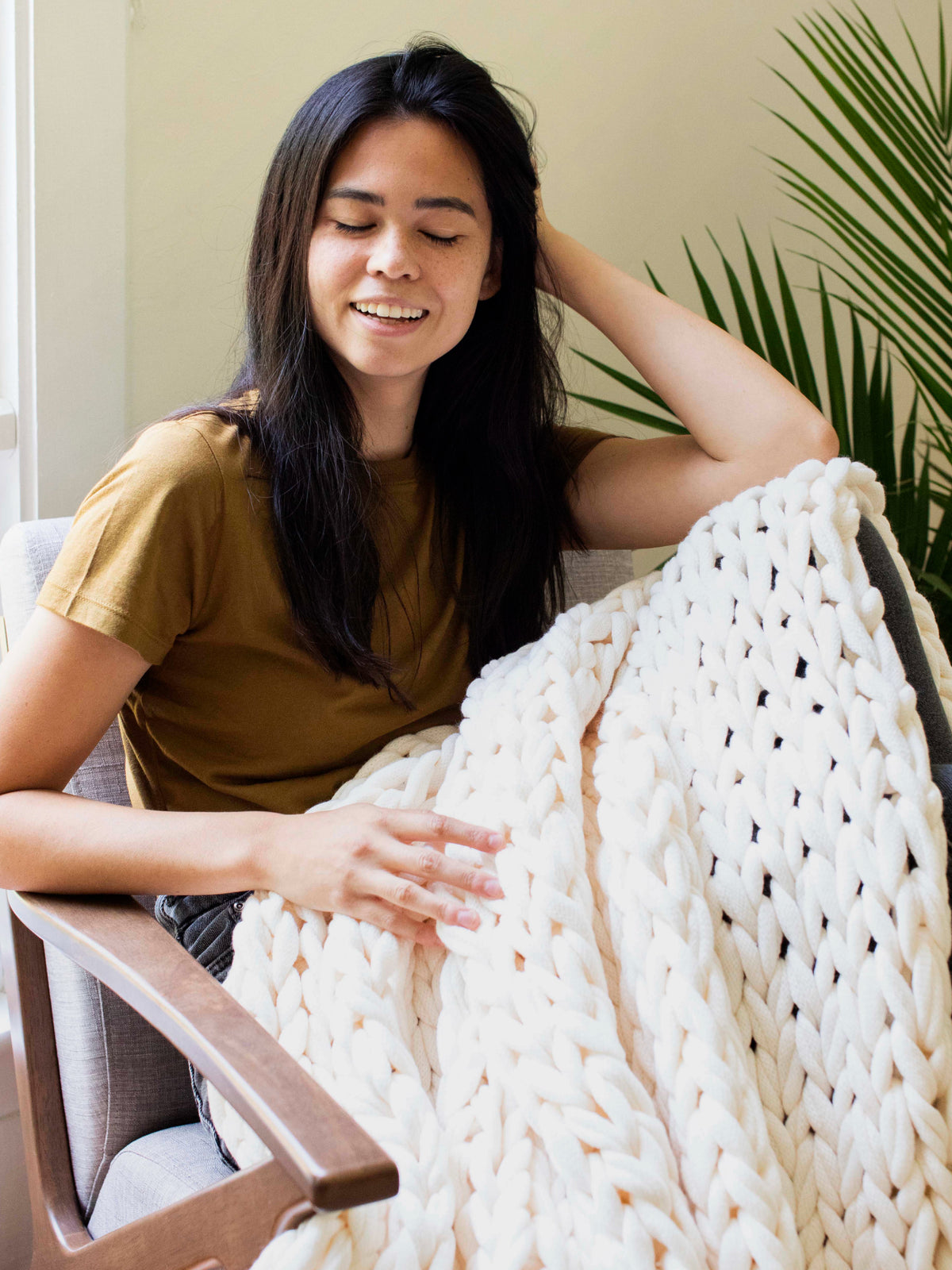 Spring collection image featuring our cream Sailors Knot Throw draped over a woman's legs.