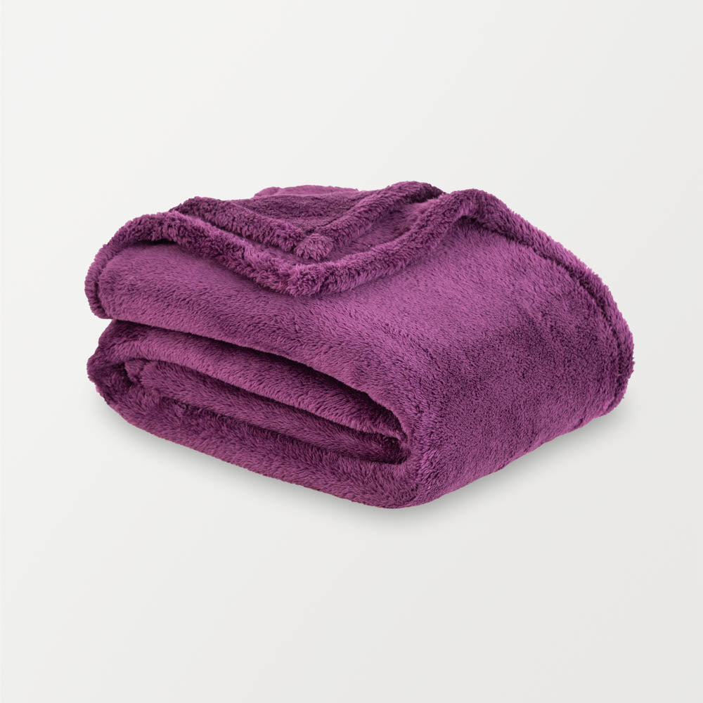 Purple extra fluffy throw folded neatly on a white surface.