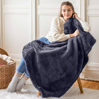 A woman sitting with a navy fluffy throw draped over her.