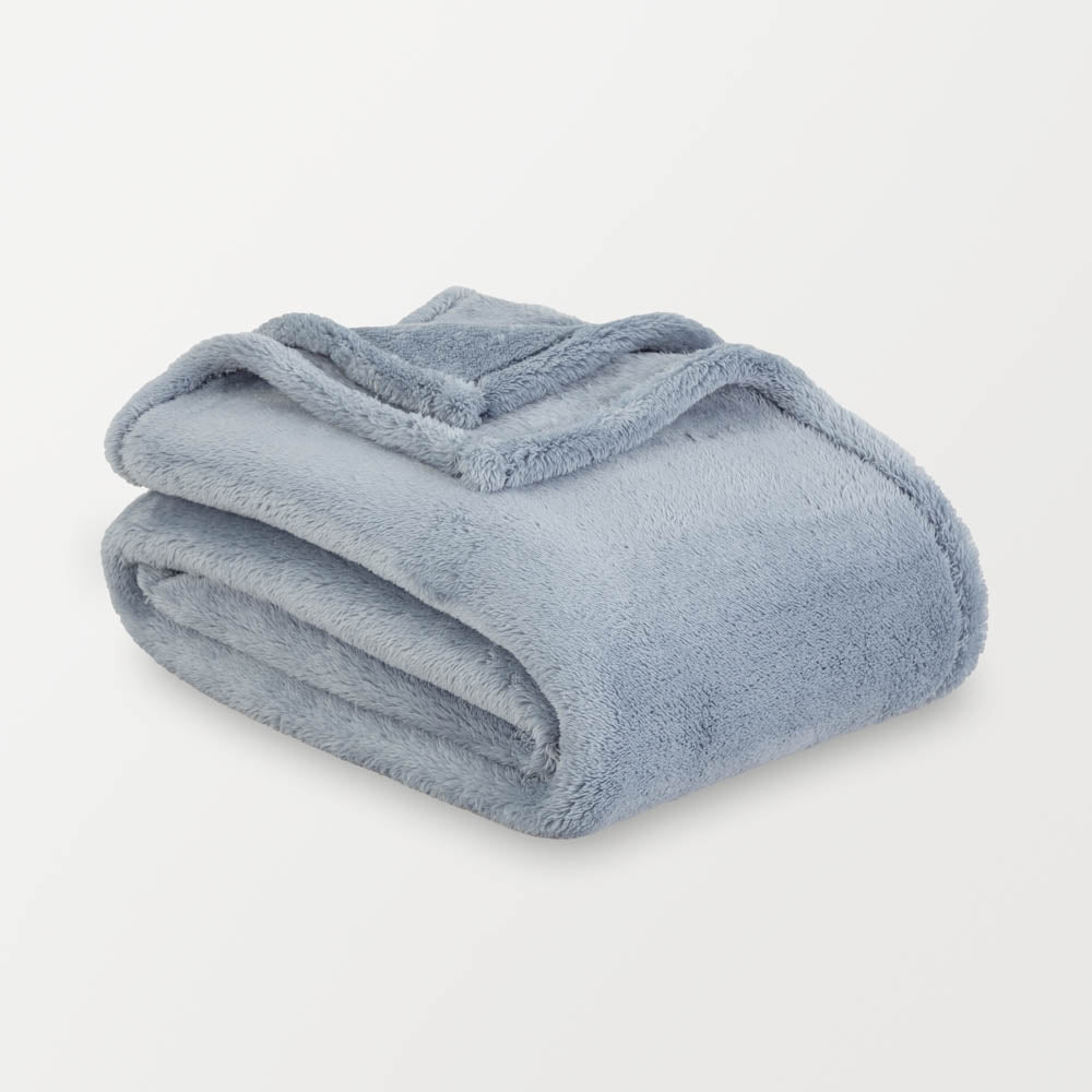 A blue extra-fluffy throw folded enatly on a white surface.