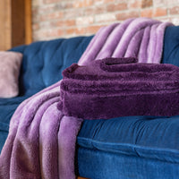 Two purple throws laid on a blue sofa.