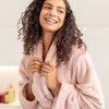 Woman wrapped in a pink robe with a blurred background