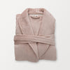 A pink VelvetLoft Luxury Plush Spa Robe folded neatly on a white surface.