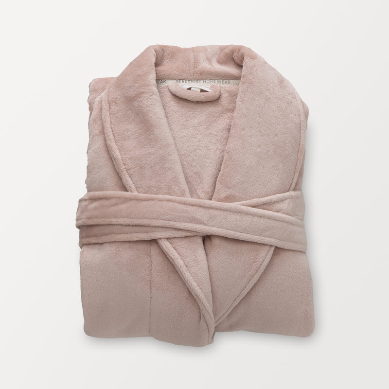 A pink VelvetLoft Luxury Plush Spa Robe folded neatly on a white surface.