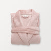 A pink VelvetLoft Luxury Plush Spa Robe folded neatly on a white surface.