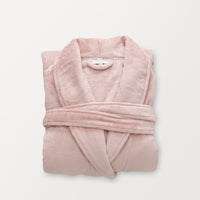 A pink VelvetLoft Luxury Plush Spa Robe folded neatly on a white surface.