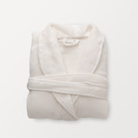 A white VelvetLoft Luxury Plush Spa Robe folded neatly on a white surface.