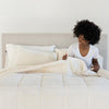 A person lounging on a bed covered with a white quilted comforter, resting their arm on the pillow.