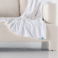 A white velvety plush throw draped neatly over a cream sofa.