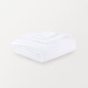 A white velvety plush throw folded neatly on a white surface.