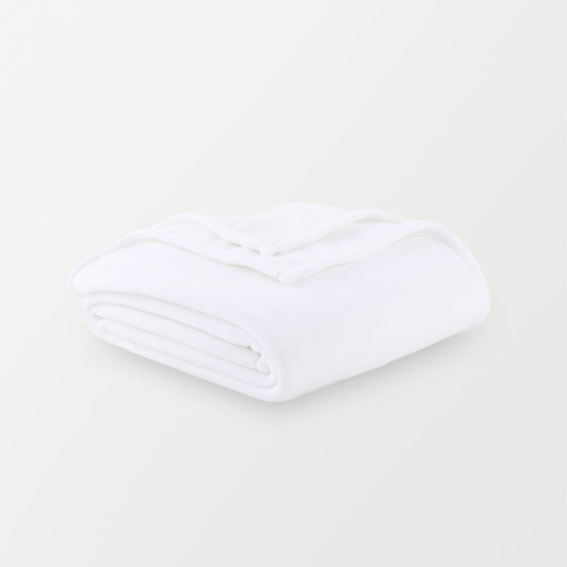 A white velvety plush throw folded neatly on a white surface.