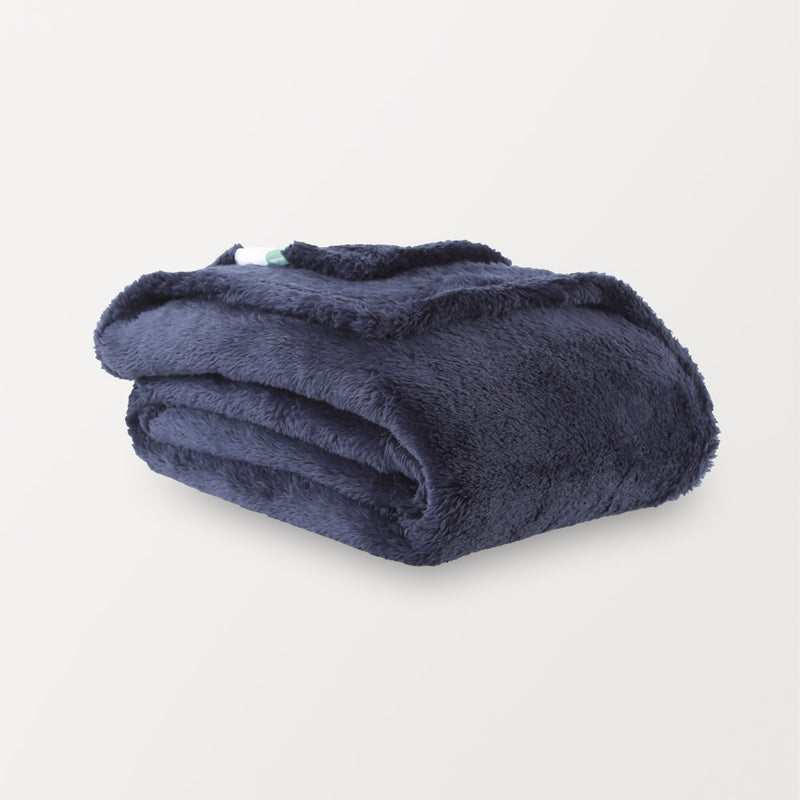 A folded navy blue Extra-Fluffy Throw resting on a white surface.