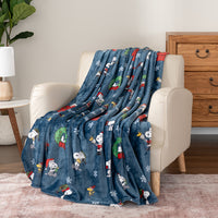Blue blanket with cartoon characters draped over a beige armchair in a room.
