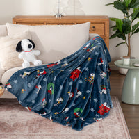 Blue blanket with festive design draped over a sofa in a living room setting.