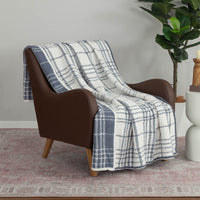 A white and blue plaid knitted throw draped neatly over a brown leather chair.