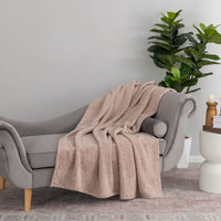 Hushed Auburn throw draped elegantly over a chair with decorative plants and lighting in the background.