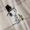 A close up of a neutral plaid snoopy and woodstock throw showing the snooth plush texture.