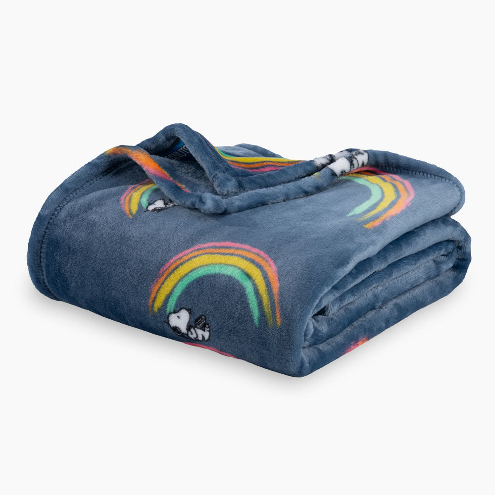 A blue rainbow snoopy throw folded neatly on a white surface.