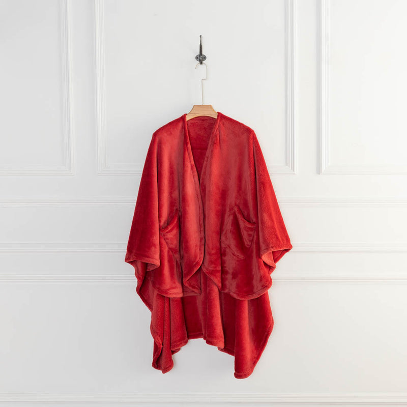 A red PrimaLush Cape Wrap displayed on a hanger in a bright, minimalist space.