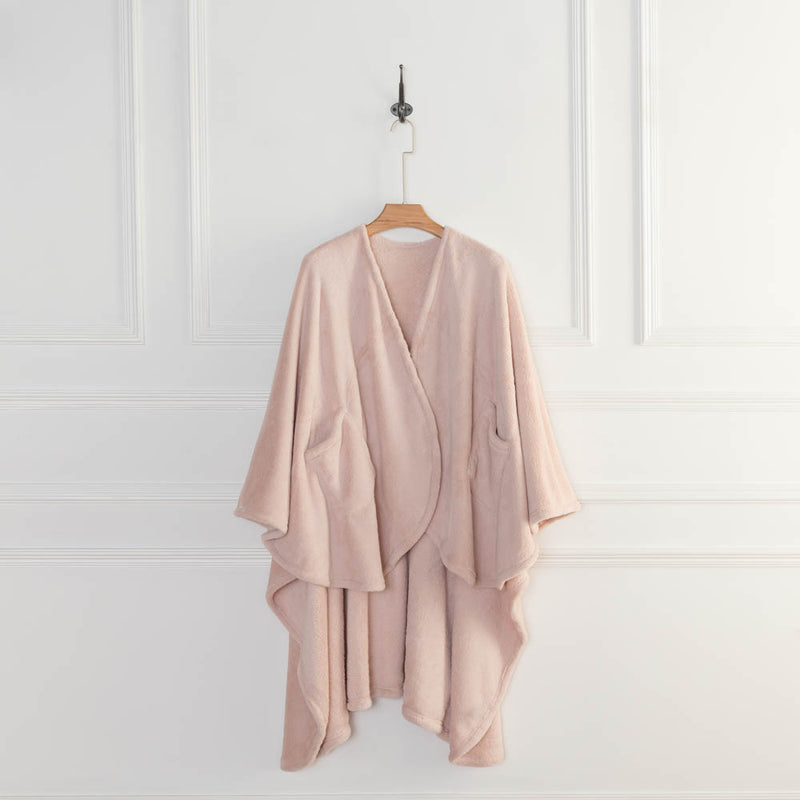 A blush pink PrimaLush Cape Wrap draped on a hanger, displayed in a bright space.