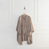 A taupe PrimaLush Cape Wrap hanging neatly on a wall hook against a white wall.