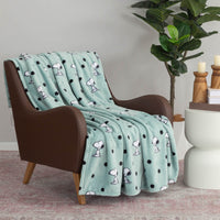 A blue polka dot snoopy throw draped neatly over a brown chair.